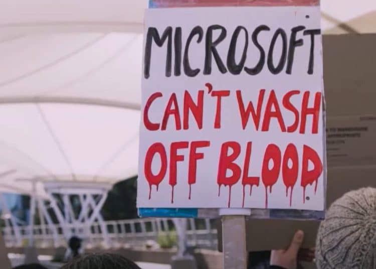 Protesters hold a placard reading "Microsoft can't wash off blood".