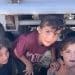 Palestinian children in Gaza climbing out from under the back of a vehicle.