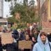 Anti-fascist counter-protesters hold placards up in a crowd reading: "Immigrants and refugees always welcome" and "Politicians and billionaires are pedophiles - and you're worried about immigrants?" Far right Newcastle