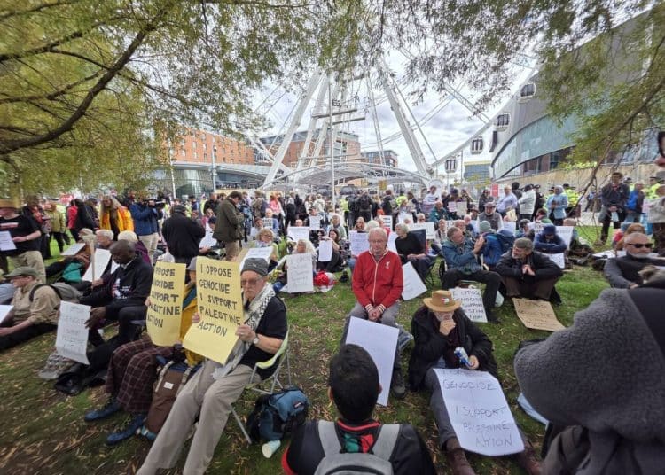 Protesters hold placards outside Labour Party conference reading "I oppose genocide. I support Palestine Action."