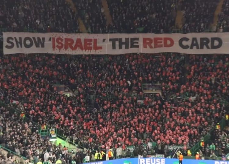 Football fans in a stadium hold an enormous banner which reads: "Show Israel the red card" Israel FIFA UEFA ban