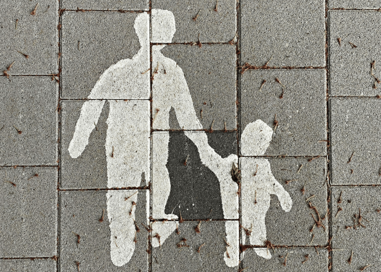 Family courts law change - image of an adult holding a child's hand painted on to the concrete