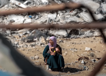 Palestinian woman and her child sit amid the wreckage of buildings Israel has turned to rubble in Gaza.