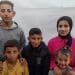 Alaa's Shamali's five children, Dima, Ibada, Salah, Abdullah, and Lina stand together in front of a displacement tent.