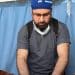 Turkish doctor Taner Kamaci in scrubs treating a child on a hospital bed hooked up to an IV drop, with blue hospital curtains behind them.