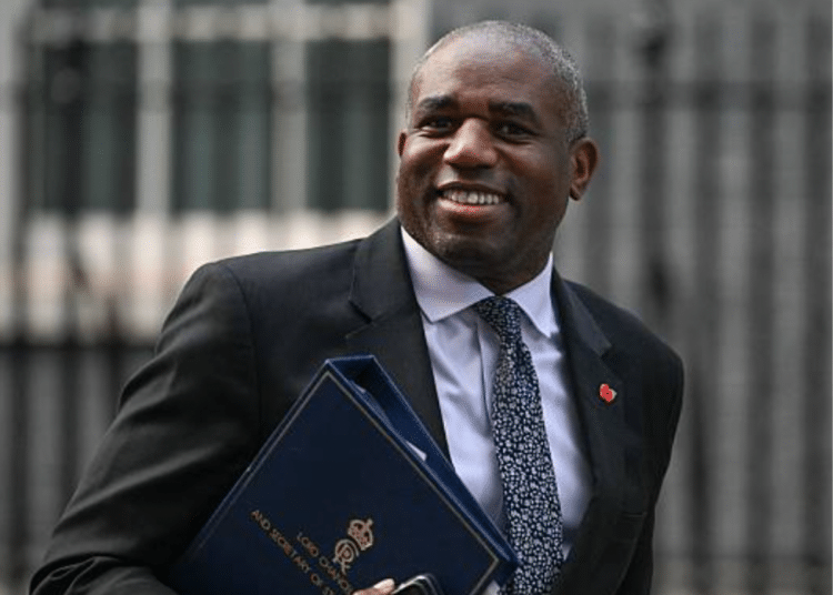 David Lammy smiles clutching a briefcase or folder at his chest in Downing Street