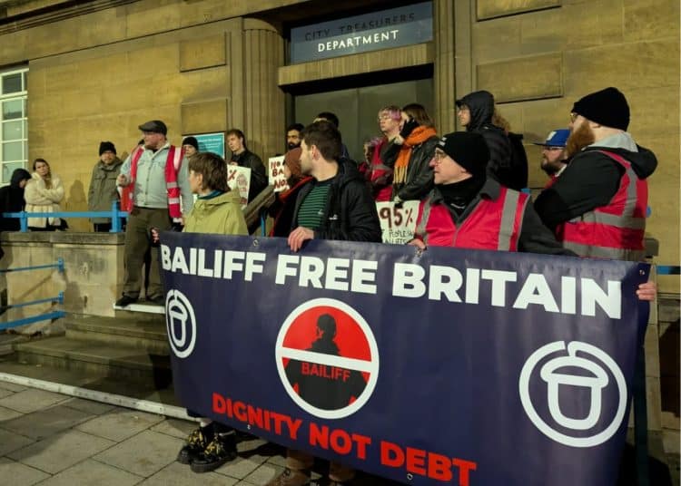 Acorn supporters outside Norwich City Hall, holding a banner saying Bailiff Free Britain Dignity Not Debt