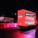 In the foreground, a bright red truck with Boycott Coca-Cola written on it. In the background, the Coca-Cola Christmas truck