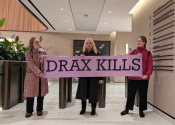 Campaigners in the Lobby of Drax HQ hold a banner saying Drax Kills