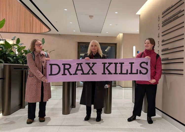 Campaigners in the Lobby of Drax HQ hold a banner saying Drax Kills
