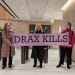 Campaigners in the Lobby of Drax HQ hold a banner saying Drax Kills