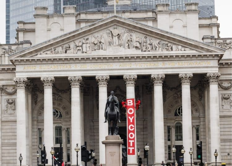 The Royal Exchange building in London with a red banner saying Boycott hung from a pillar by activists from Boycott Bloody Insurance