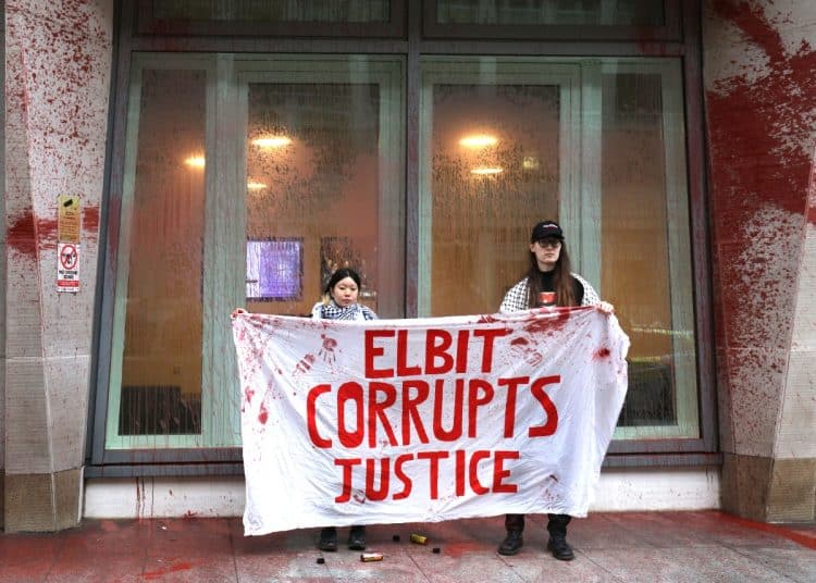 Supporters of the hunger strikers outside the Ministry of Justice hold a banner saying Elbit Corrupts Justice