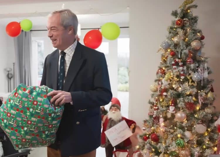 Nigel Farage holding a present next to a Christmas tree