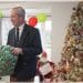 Nigel Farage holding a present next to a Christmas tree
