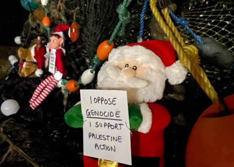 Christmas toys holding signs that say I Oppose Genocide. I Support Palestine Action and I Oppose Genocide. I Support The Hunger Strikers