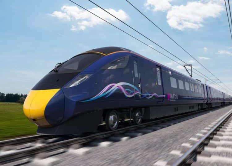 A navy blue train against a blue sky on a grey rail track