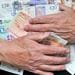 Hands holding UK bank notes to illustrate FTSE 100 CEO pay