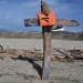 A cross made with driftwood from the Cutro shipwreck. A lifejacket and a training shoe hang from the cross