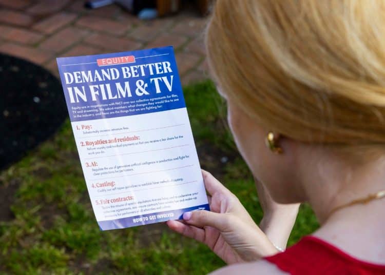 A person reads a flyer for Equity - PACT negotiations including AI protections