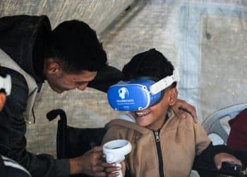 A therapist helps a child use a VR headset for trauma therapy, Gaza