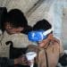 A therapist helps a child use a VR headset for trauma therapy, Gaza