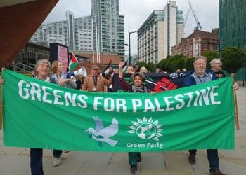 People holding a banner saying Greens For Palestine. Calls for Green Party to be anti-Zionist.