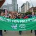 People holding a banner saying Greens For Palestine. Calls for Green Party to be anti-Zionist.