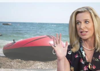 Katie Hopkins in front of a dinghie on a beach