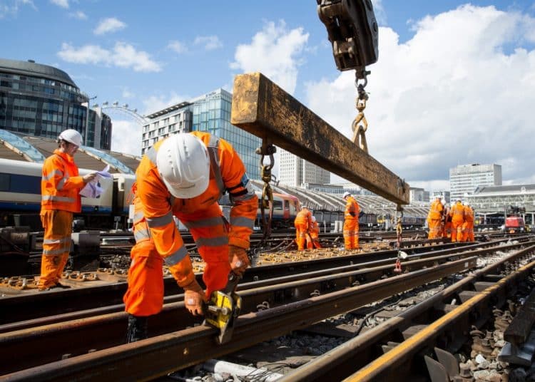 Network Rail workers in orange hi-vis overalls and white hard hats