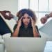 Image illustrating workplace stress. A tired looking woman sits behind a laptop as hands holding a phone, a watch, a report, a book, intrude from the sides