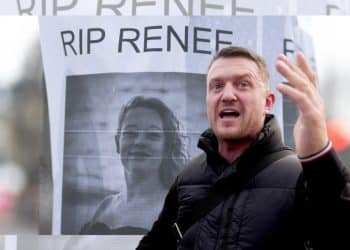 Tommy Robinson in front of an image of Renee Good