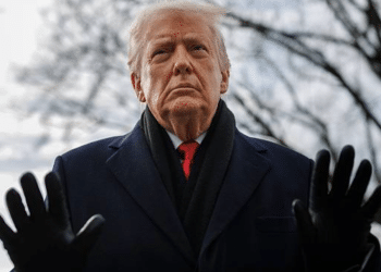 Donald Trump dressed in a suit and smart coat looking unhappy