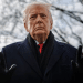 Donald Trump dressed in a suit and smart coat looking unhappy