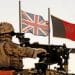 UK military in Afghanistan. A gunner in front of a union flag and an Afghan flag Paul Dixon