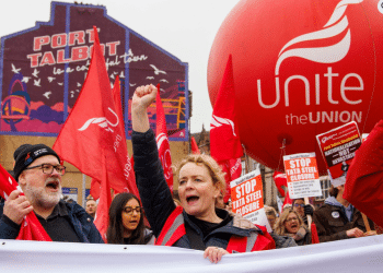 Unite members protest over Tata Steel with Sharon Graham up front, wearing a flourescent jacket and holding her fist in the air