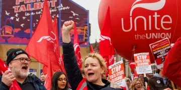Unite members protest over Tata Steel with Sharon Graham up front, wearing a flourescent jacket and holding her fist in the air