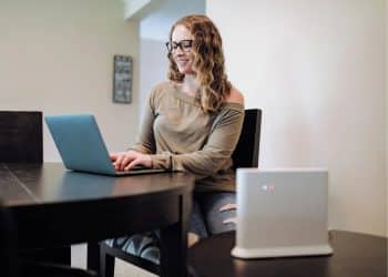 A woman working at a laptop with a broadband router in the foreground