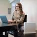 A woman working at a laptop with a broadband router in the foreground