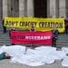Banners outside St Paul's saying Don't Crucify Creation and Stop Rosebank with people under white shrouds in front