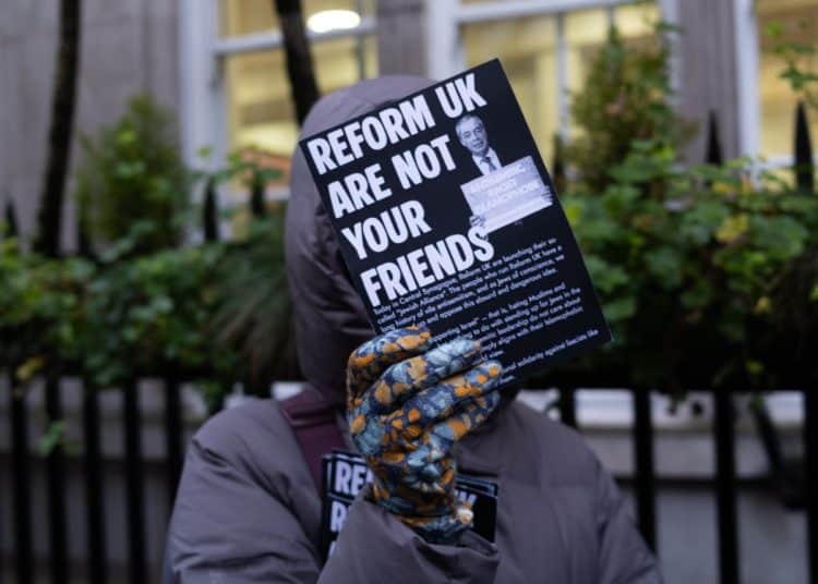 Protester holds flyer saying Reform UK Are Not Your Friends at launch of Reform Jewish Alliance