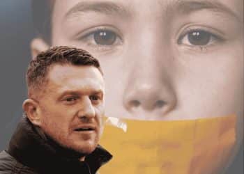 Tommy Robinson in front of an image of a child with tape on their mouth