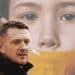 Tommy Robinson in front of an image of a child with tape on their mouth