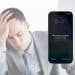 A man with his head in his hands and a locked iPhone