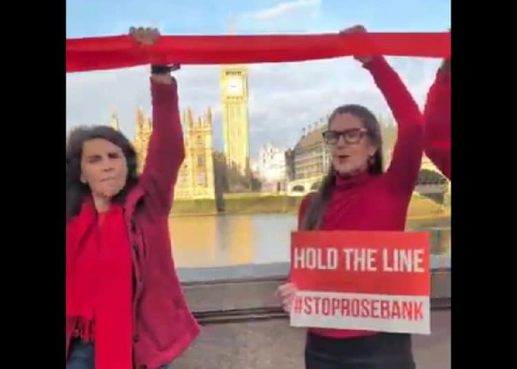 Fossil Free London protesters across the Thames from parliament hold a red ribbon and a sign saying Hold The Line #StopRosebank Rosebank