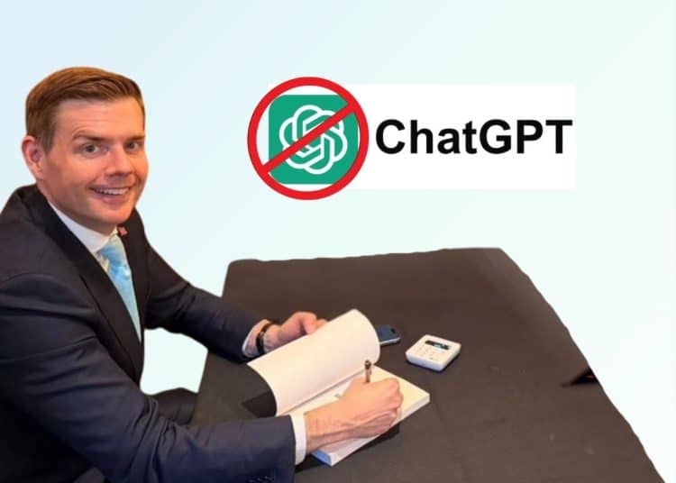 Reform member Matt Goodwin sits at a desk smiling. A 'No ChatGPT' logo is in the background of the photo