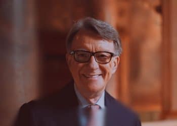 Peter Mandelson in black-rimmed glasses smiles at the camera