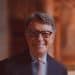 Peter Mandelson in black-rimmed glasses smiles at the camera