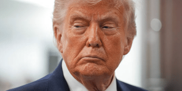 US president Donald Trump with his mouth slightly curled, looking stern with his gaze down and slightly away