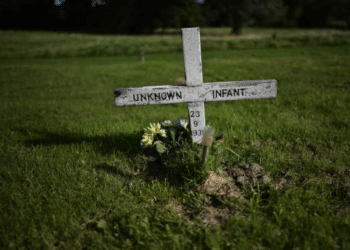 DWP cutting benefits of women who received compensation after surviving mother and baby homes - image shows an unmarked infant grave with a cross that reads 'unknown infant'